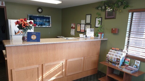 A reception desk with a clock, framed certificates, and a plant. - Split Mountain Motel (Vernal)