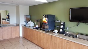 A kitchen with wooden cabinets, a microwave, a coffee machine, and a television on the wall. - Split Mountain Motel (Vernal)