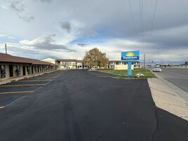 Un Days Inn by Wyndham con estacionamiento, edificios tipo motel y cielo despejado.
