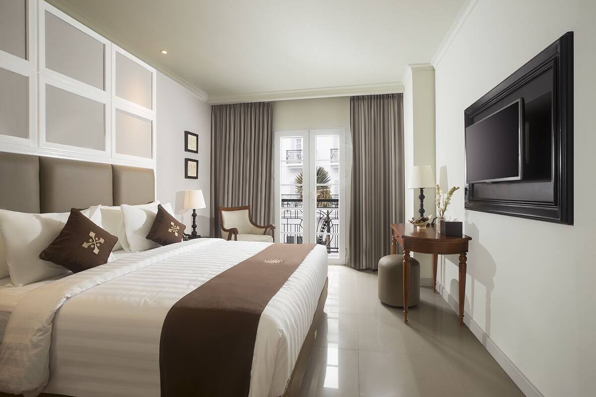 A hotel room with a large bed, a TV, a small table, and a chair.