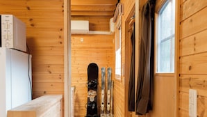 Interior de una cabaña de madera con un pasillo que conduce a un área para guardar esquíes.