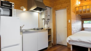 Una cabaña compacta y moderna con kitchenette, cama y baño.