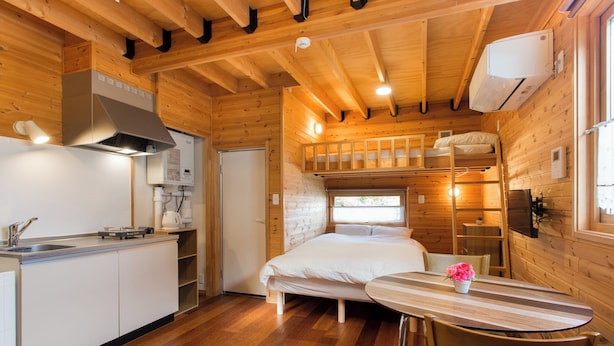 Una habitación compacta tipo cabaña, con cocina americana, cama y zona de comedor.