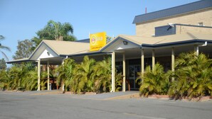 A hotel with a prominent 'XXX GOLD' sign, covered outdoor seating area, and palm trees in the foreground. - Capricorn Hotel (Blackwater)