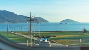 A coastal view with a statue, power lines, and a road leading to the sea. - Pension Manoa (Namhae)