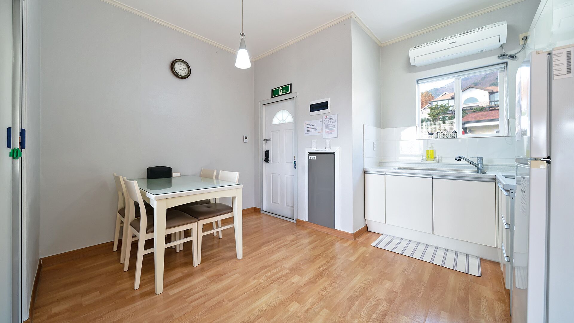 A compact kitchen with a dining area, a refrigerator, a sink, and a window with a view.