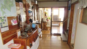 A hallway with wooden floors, a globe, and various items on shelves. - Minshuku Mutsukari (Furano)