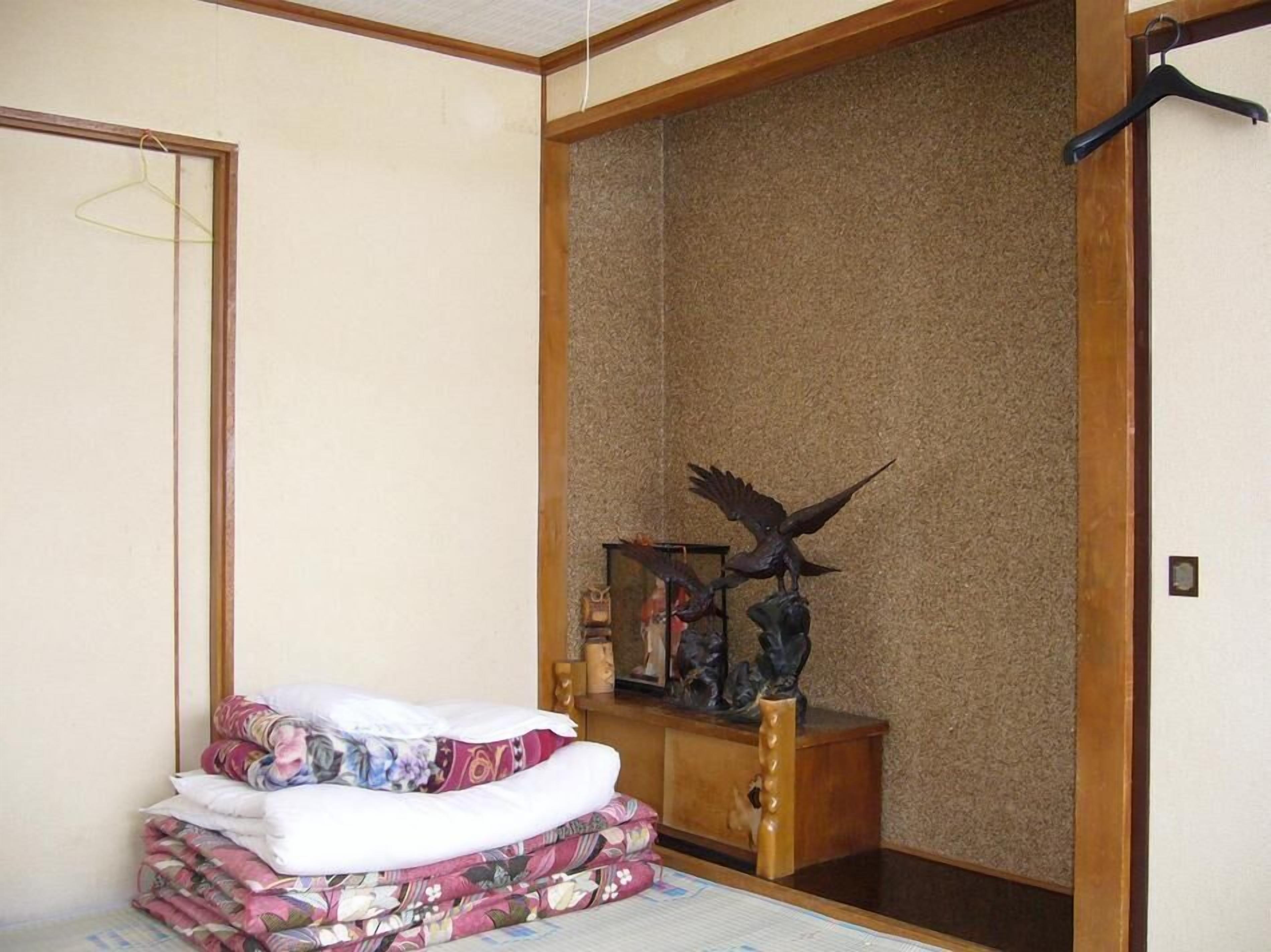Ein Zimmer mit einem Bett, einem Holzschrank und einem schwarzen Kleiderbügel.