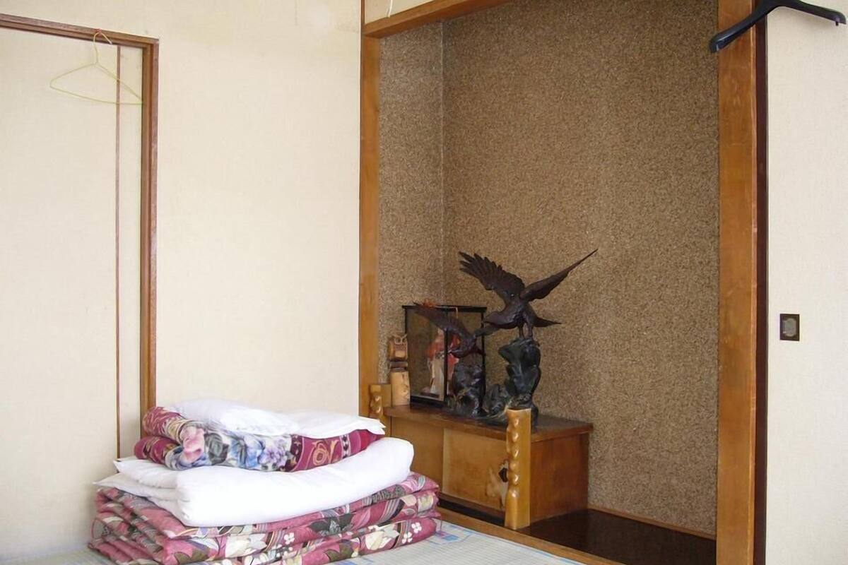 Una habitación con una cama, un armario de madera y un perchero negro colgante.