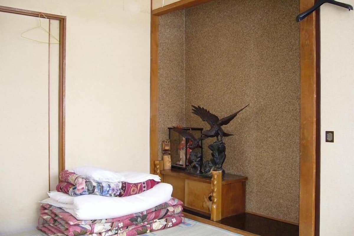 A room with a bed, a wooden cabinet, and a hanging black hanger.
