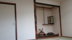 A traditional Japanese room with tatami flooring, a sliding door, a shelf with decorative items, and a hanging lantern. - Minshuku Mutsukari (Furano)