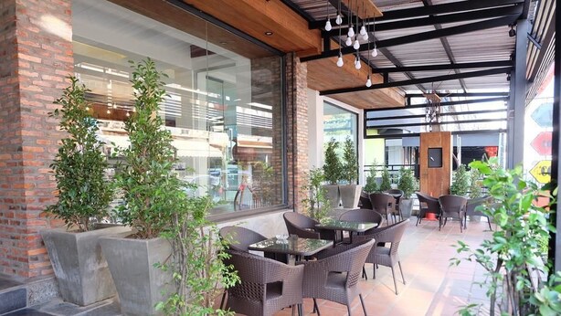 An outdoor patio area with wicker furniture, potted plants, and a brick wall. - Lao Silk Hotel (Vientiane)