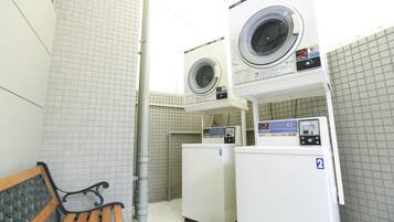 A laundry room with two washing machines, a bench, and tiled walls.