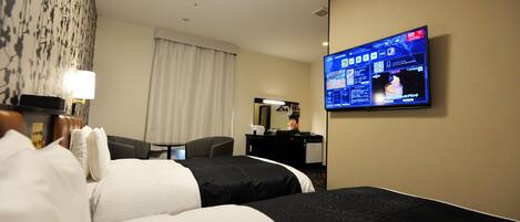 Habitación de hotel con dos camas, un escritorio, un televisor y una ventana con cortinas.
