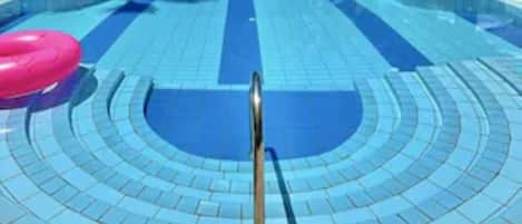 Alberca al aire libre, sombrillas en la alberca y camastros