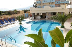 Una piscina al aire libre, sombrillas, sillones reclinables de piscina