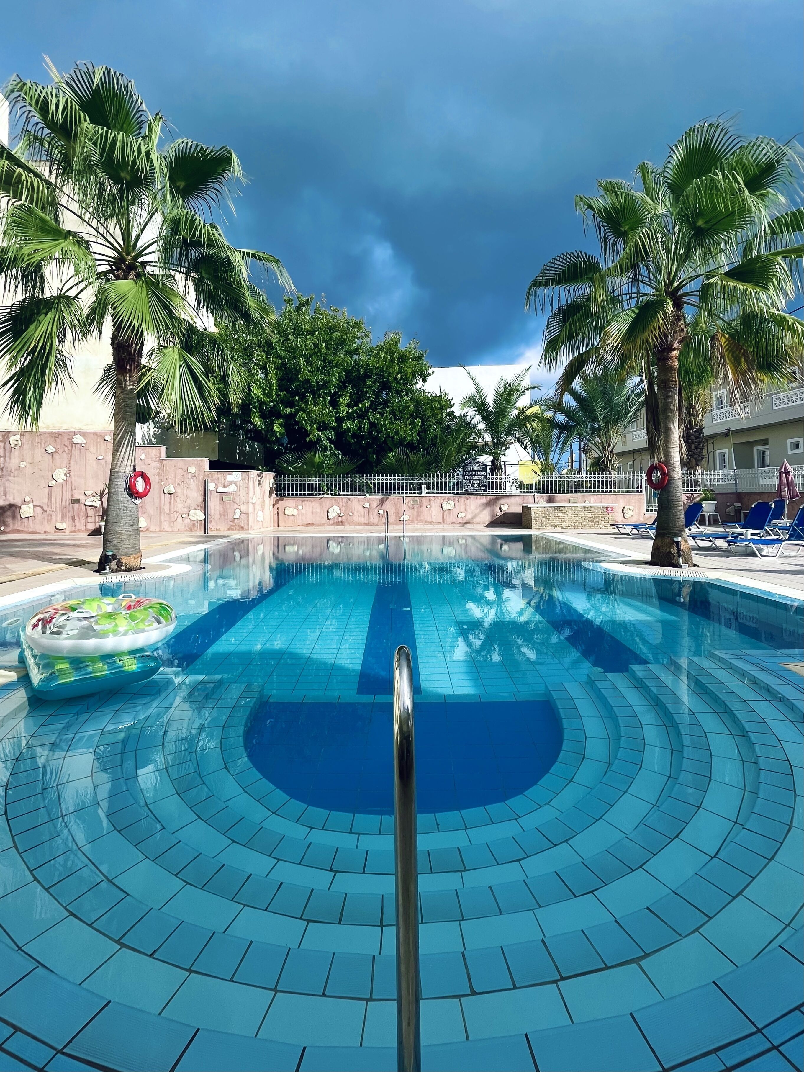 Una piscina al aire libre, sombrillas, sillones reclinables de piscina