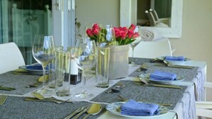 A table set for dining with wine glasses, cutlery, and a vase of flowers.