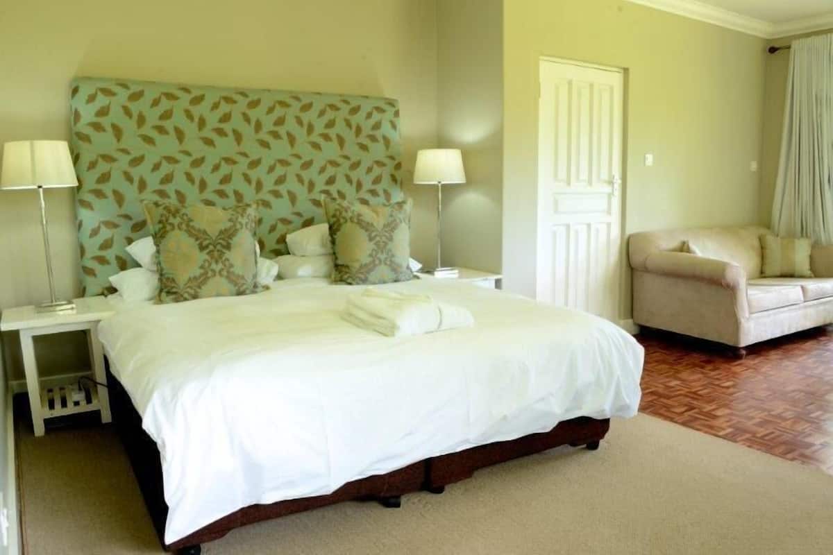A neatly arranged bedroom with a large bed, two bedside tables, a chair, and a door.