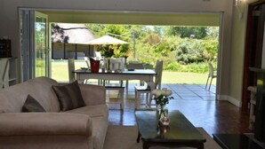 A living room with a sofa, coffee table, and a dining area with chairs and an umbrella.