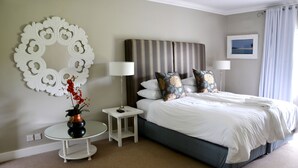 A neatly arranged hotel room with a large bed, two bedside tables, a decorative wall piece, and a framed picture.