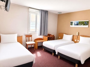 A hotel room with two beds, a desk, a chair, a telephone, and a window with curtains.