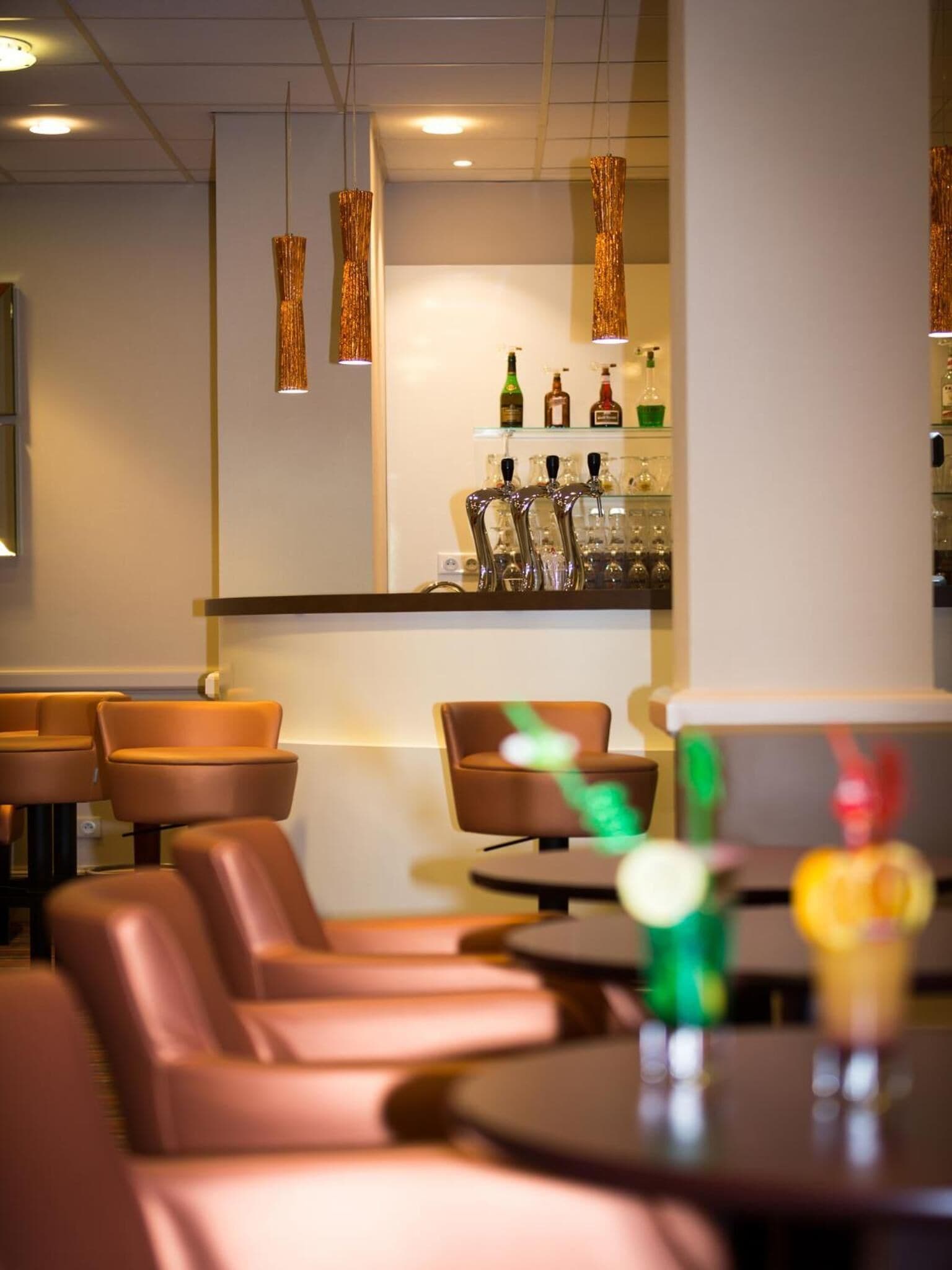 A bar area with leather seating and a counter displaying bottles and glasses.