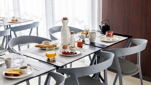 Desayuno preparado para dos personas, con tostadas, cereales, fruta y bebidas.