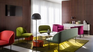 Una sala de estar moderna con un televisor de pantalla plana, una mesa de centro redonda y sillas coloridas.