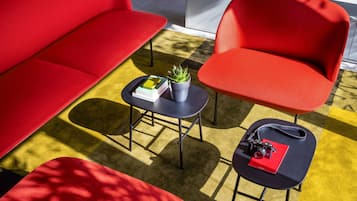 A modern living room with a red sofa, a red armchair, and a small table with a plant and books.