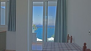 Ein Schlafzimmer mit Bett, Meerblick und Balkon mit Stuhl und Sonnenschirm.