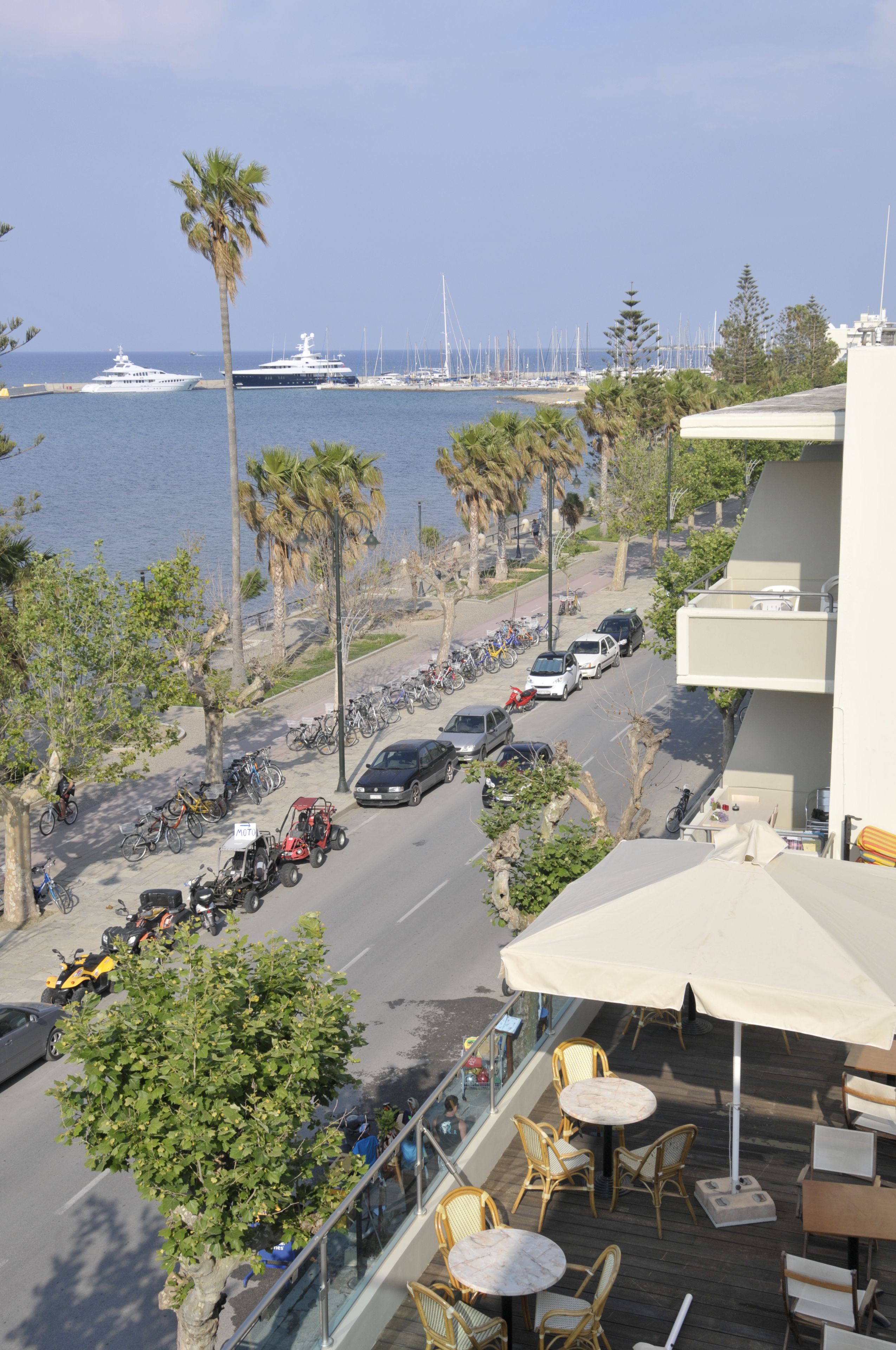 A balcony with outdoor seating overlooking a marina with yachts and boats.