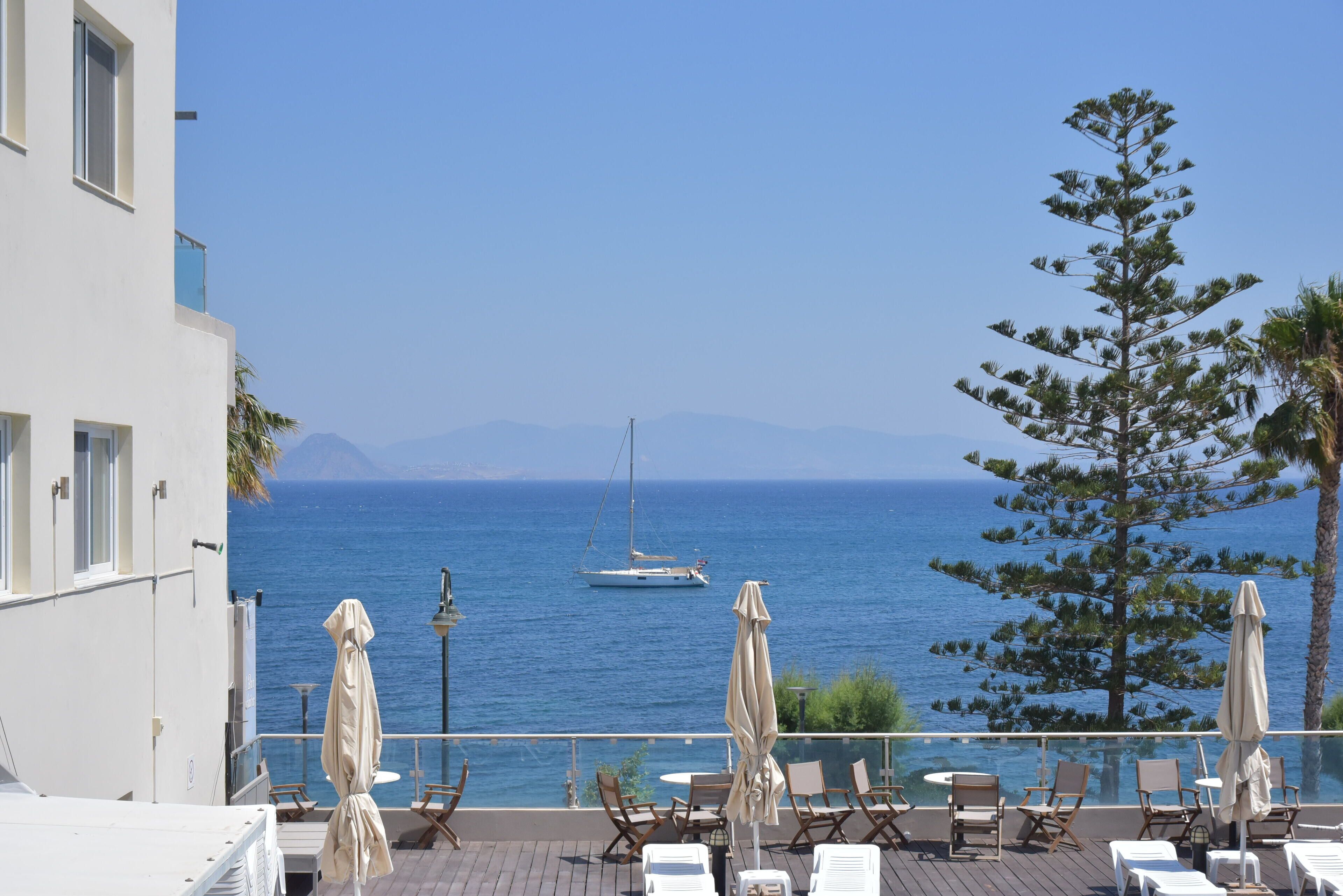 A balcony with outdoor seating and a view of the sea.