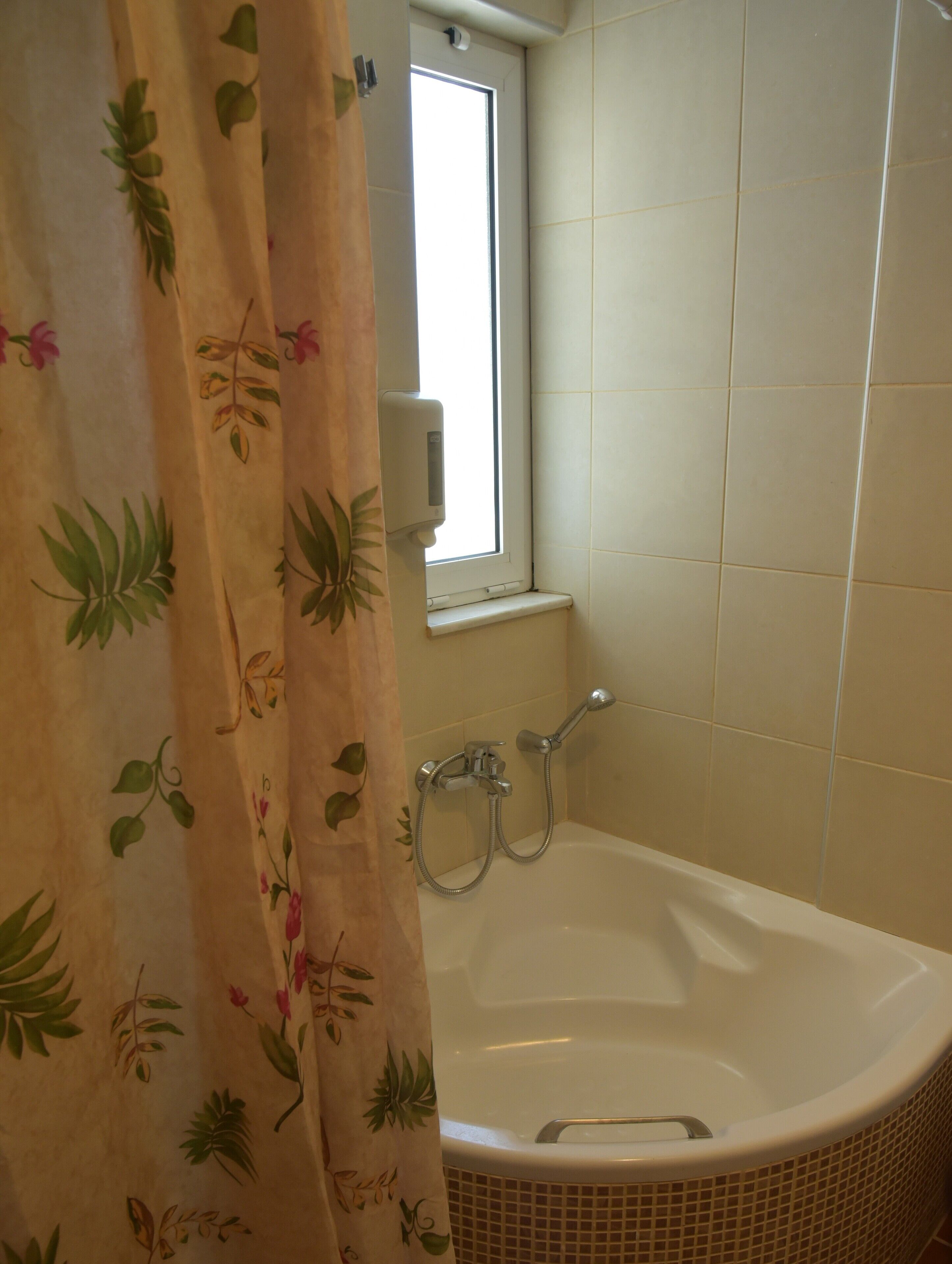 Ein Badezimmer mit einer Badewanne, einem Fenster und einer Dusche.
