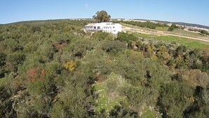 A white building with a flat roof, surrounded by dense greenery and a hilly landscape. - Centro de Naturaleza Cañada Verde (Hornachuelos)