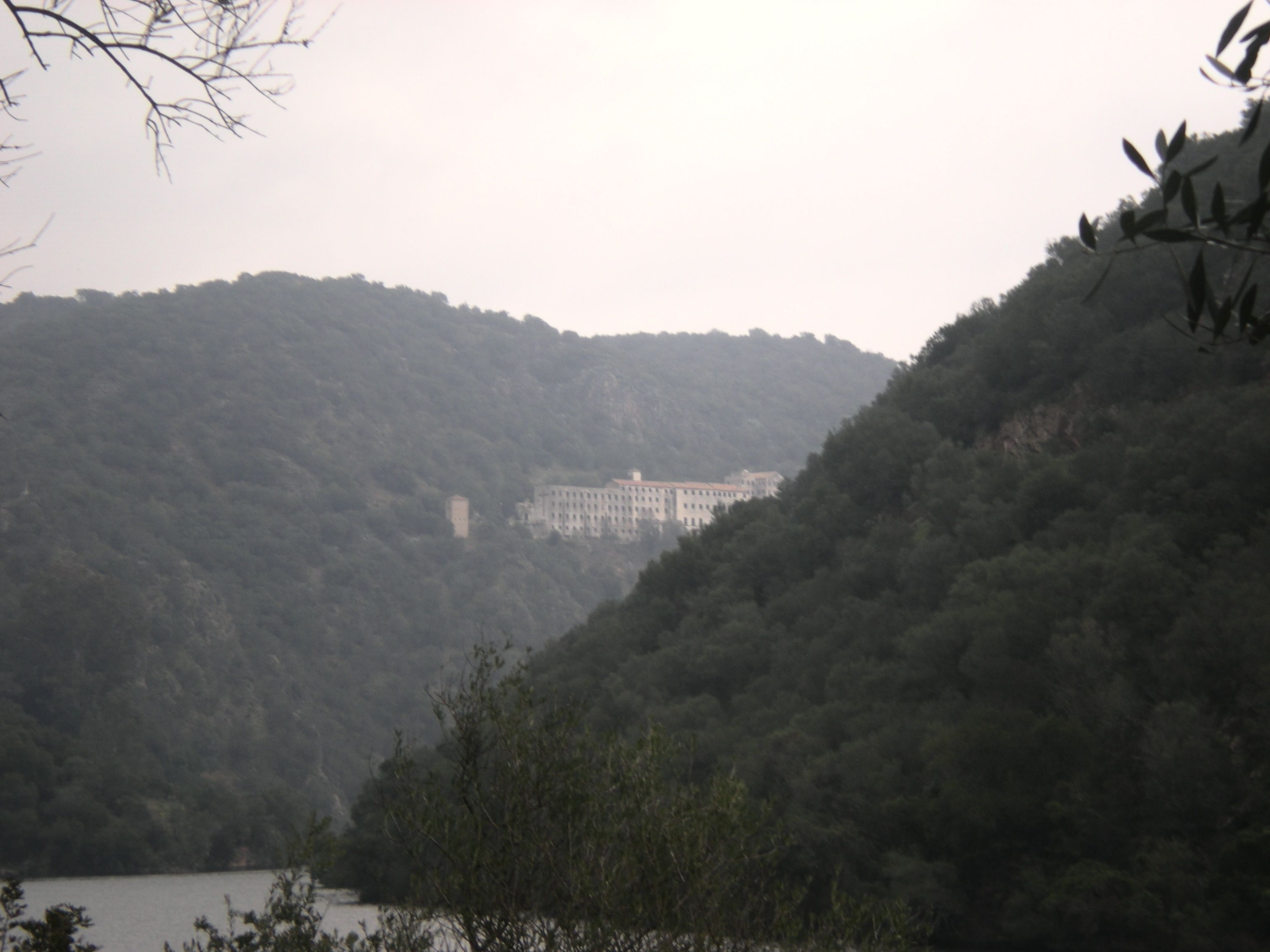 A large building surrounded by forested hills.