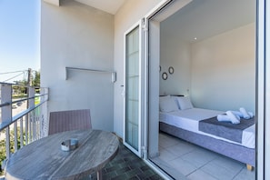 A balcony with a table and a bed in the adjacent room. - Angela Hotel and Apartments (Corfu)