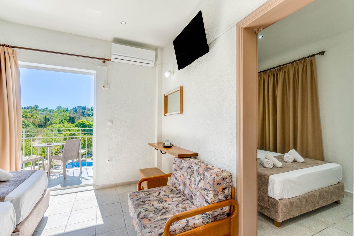 A hotel room with a balcony, a bed, a sofa, and a small table.