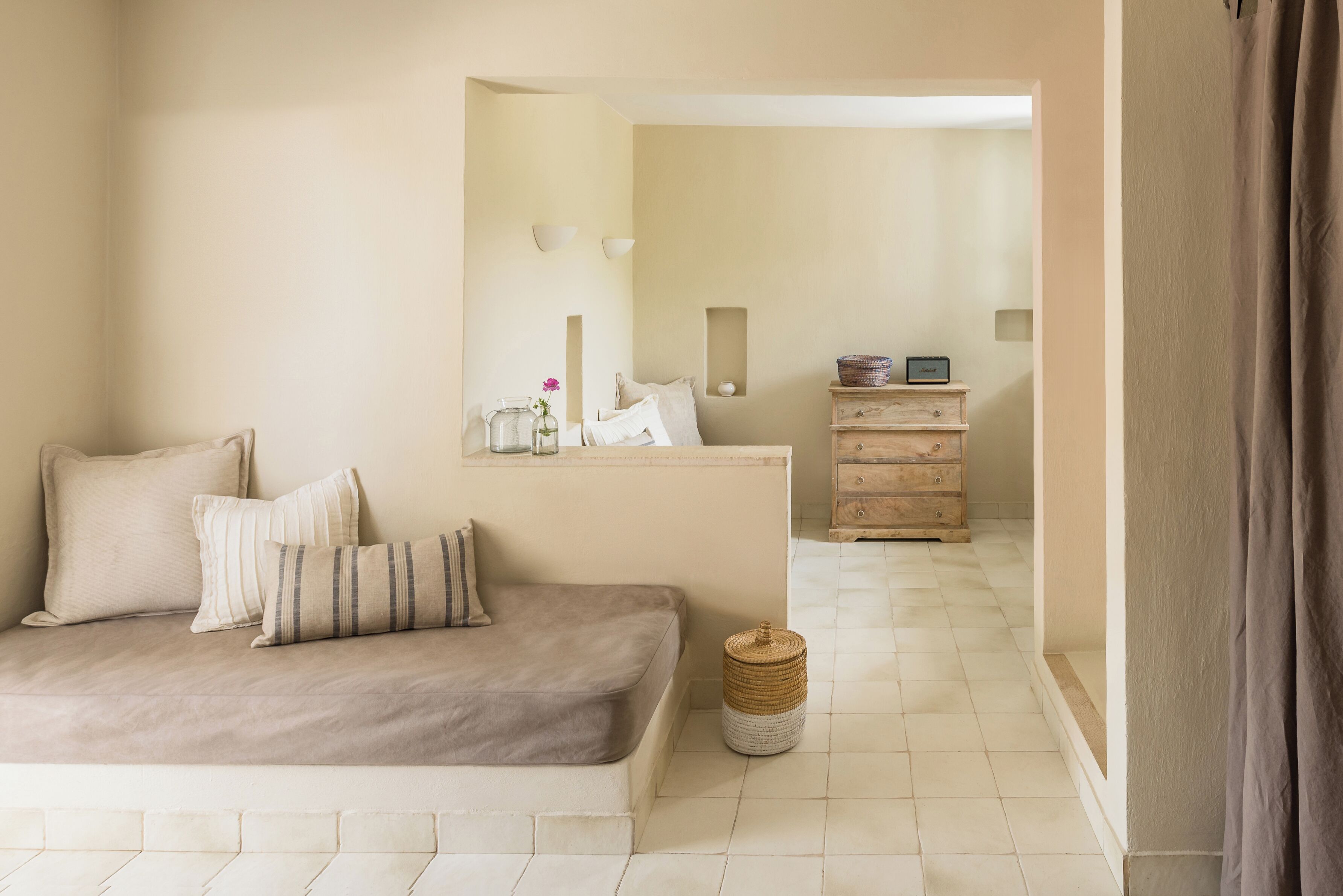 Una habitación en tonos neutros con un sofá, un pequeño aparador de madera y una cesta de mimbre.