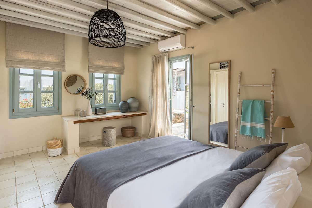Un dormitorio con cama, ventana con vistas, espejo y lámpara colgante.