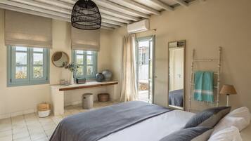 A bedroom with a bed, a window with a view, a mirror, and a hanging light fixture.