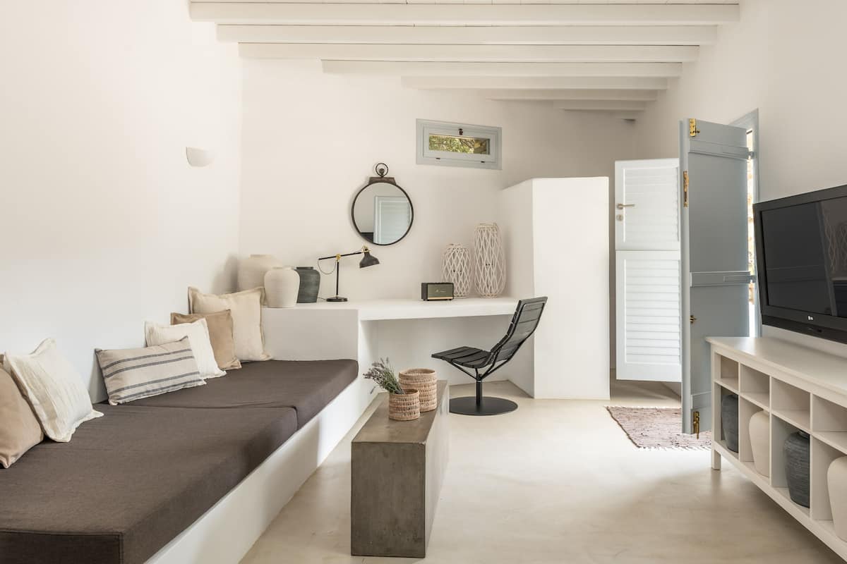 Una sala de estar moderna con un sofá, un escritorio, una silla, un televisor y una estantería.