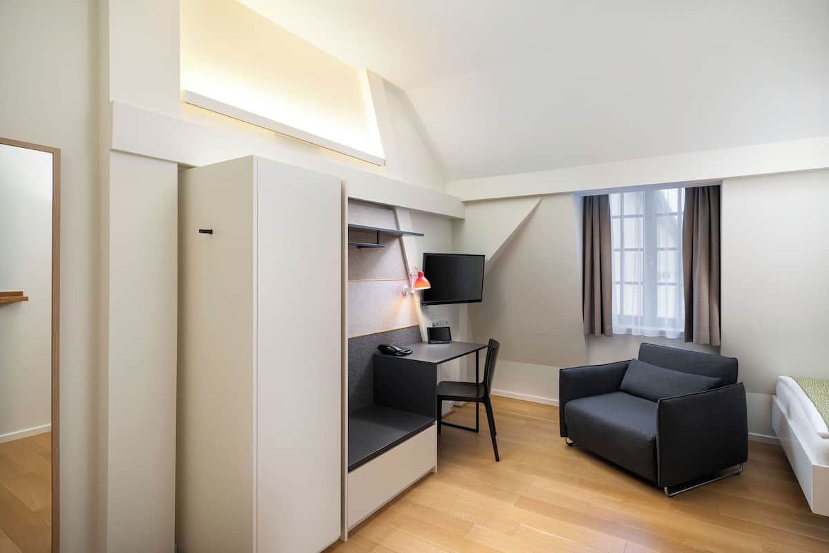 Una habitación pequeña con escritorio, silla y sofá.