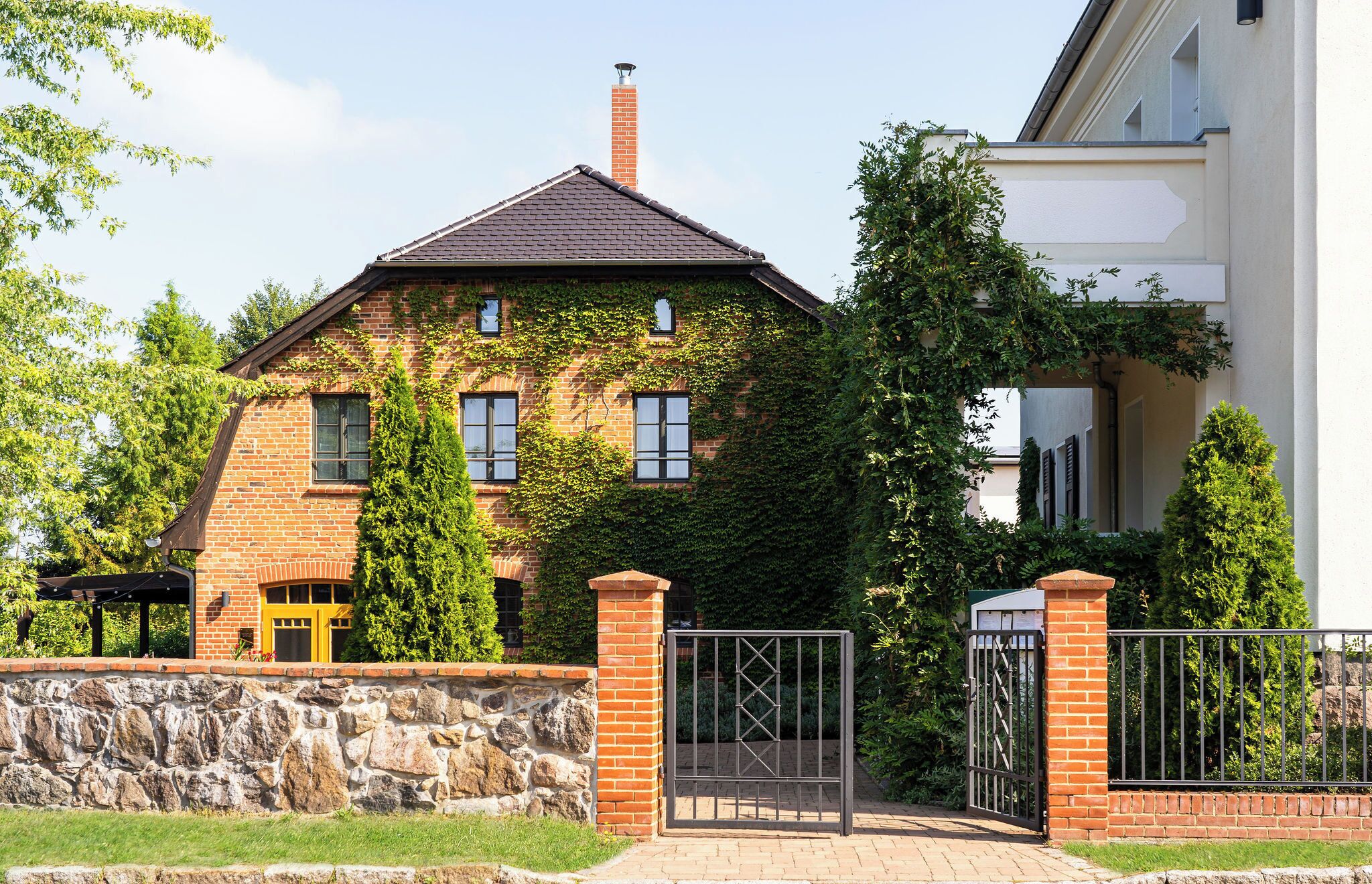 Een bakstenen huis met een stenen muur en een metalen poort.