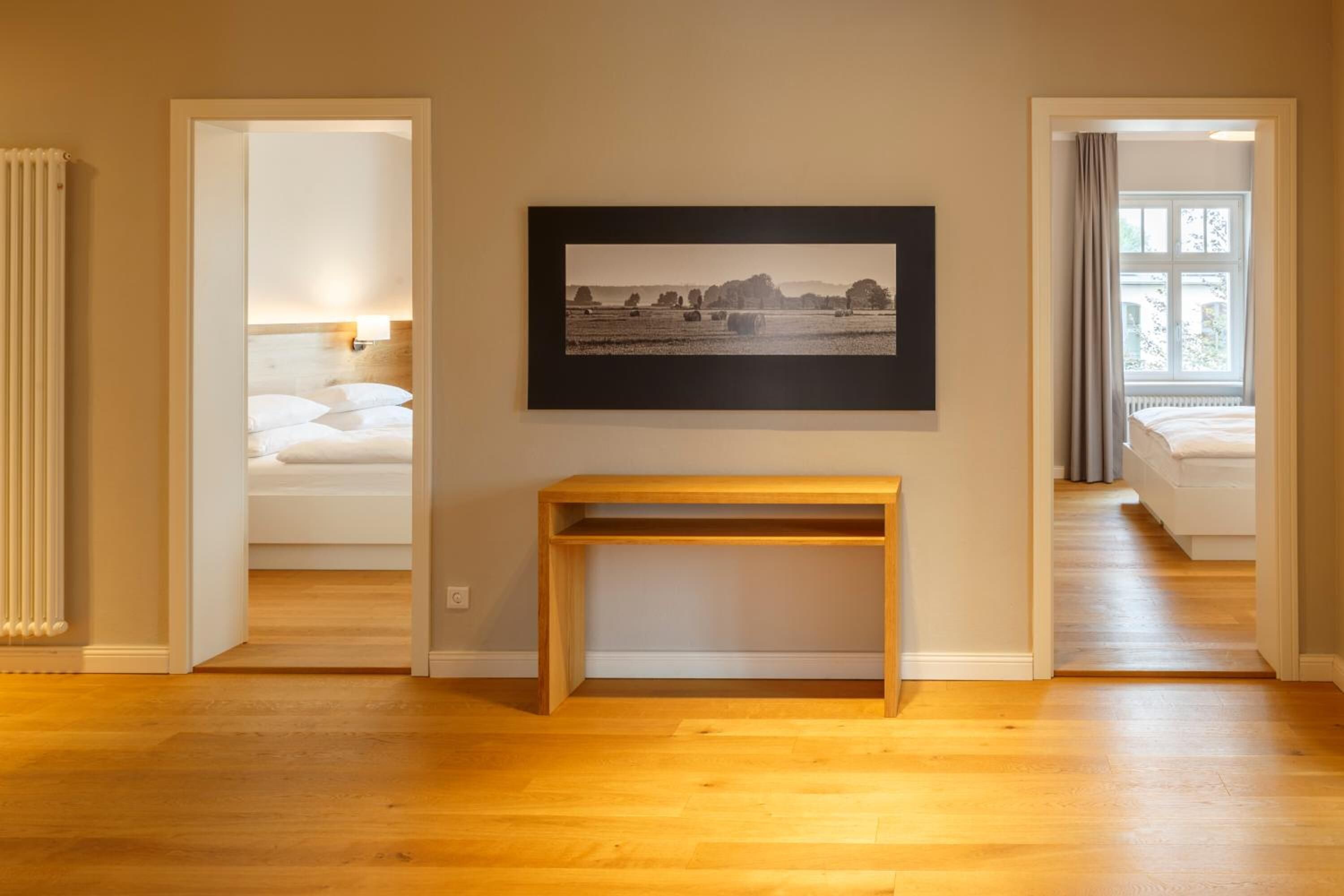 Hotellihuone, jossa on puulattia, seinällä kehystetty taulu ja valkoisilla lakanoilla pedattu sänky.