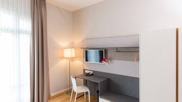 A modern hotel room with a desk, chair, and a mounted TV.