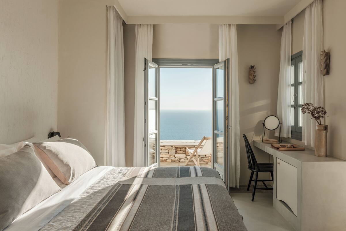 Un dormitorio con cama, escritorio y vista al mar.