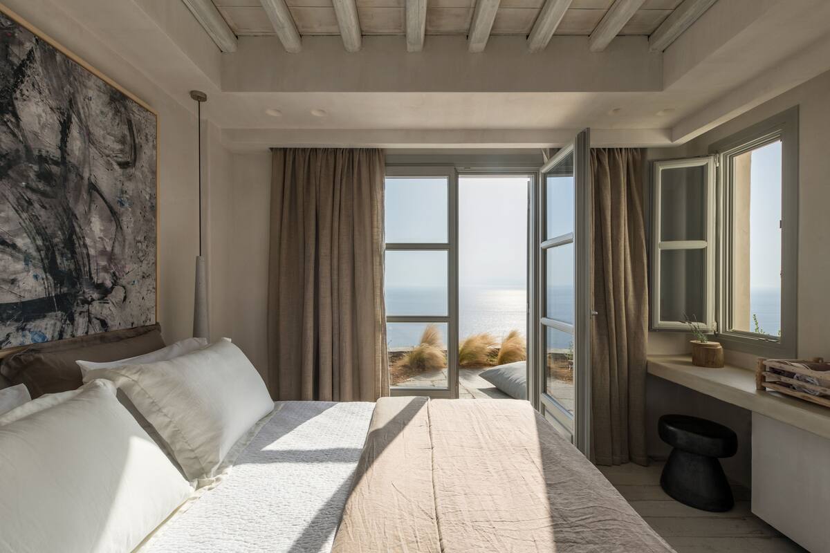 Un dormitorio con una cama grande, vista al mar y diseño moderno.