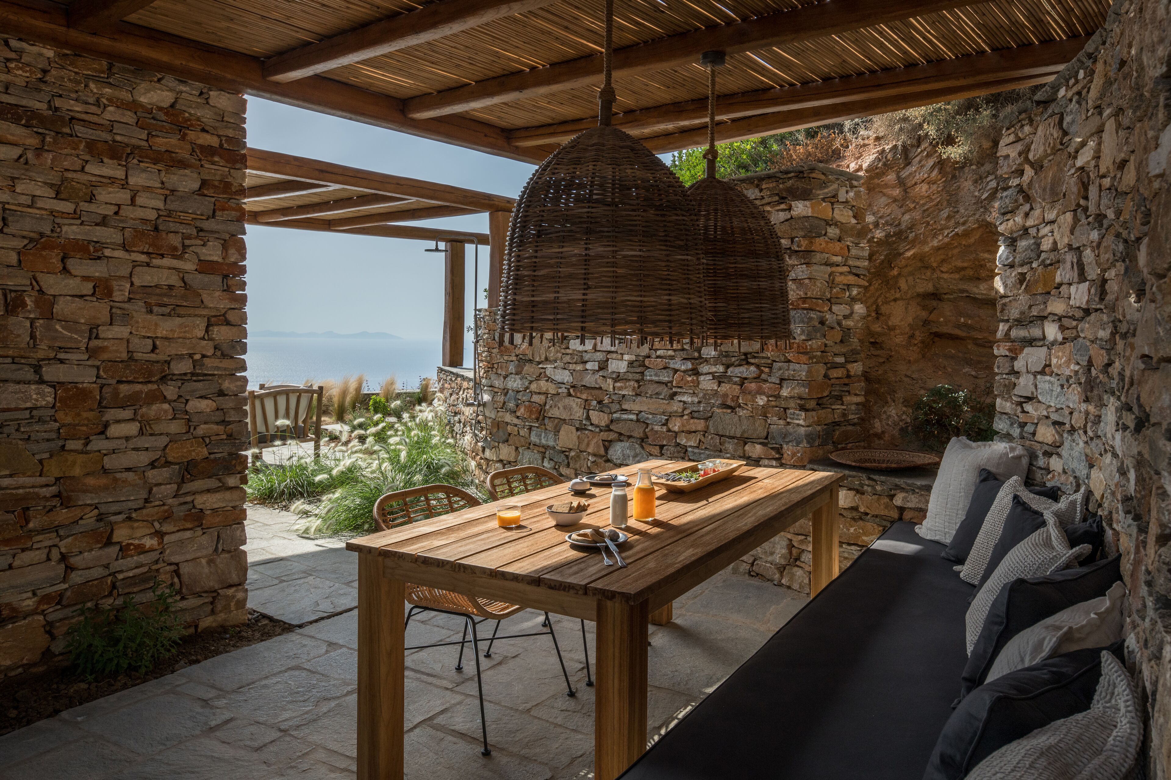 A stone-walled patio with a wooden table and seating area, overlooking a scenic landscape.