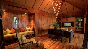 Una sala de estar acogedora con techo de madera, un sofá con cojines, un televisor y una planta.